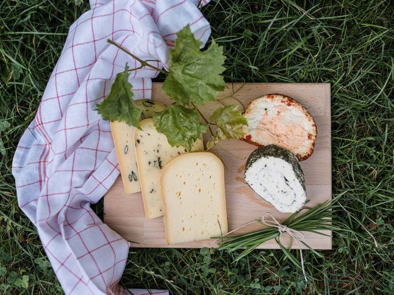 Schnittkäse und Frischkäse appetitlich auf einem Holzbrett angerichtet