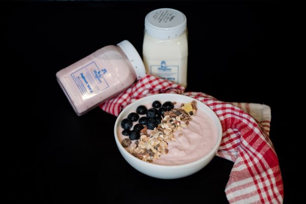 Zwei Müslischalen mit Joghurt und zwei Joghurtbecher
