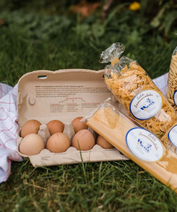 Frische Hühnereier in einer Schachtel und Eiernudeln in der Verpackung