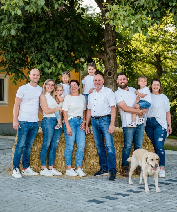 Familie Wagner, 6 Erwachsene, 4 Kinder und 1 Hund stehen unter einem grünen Baum