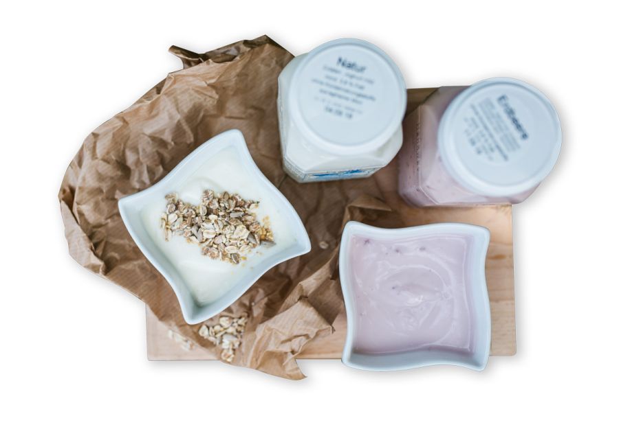 Zwei Müslischalen mit Joghurt und zwei Joghurtbecher